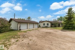 Expansive gravel driveway leading to a multi-car garage with three white garage doors - 