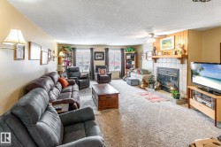 Living area with carpet flooring, a tiled fireplace, a textured ceiling, and a ceiling fan - 