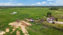 Expansive rural property featuring a vast green landscape, multiple structures, and a clear pond - 