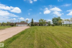 Expansive green lawn bordering a long gravel driveway - 
