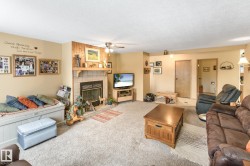 Living room featuring a tiled fireplace, a textured ceiling, a ceiling fan, and carpet flooring - 