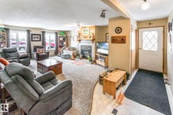 Living room with a textured ceiling, a tiled fireplace, a ceiling fan, and light tile patterned floors - 