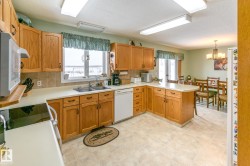 Kitchen with a peninsula, white appliances, light countertops, backsplash, and a textured ceiling - 