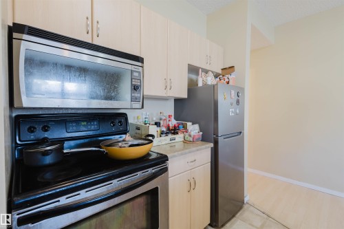 Kitchen with stainless steel appliances, light countertops, light wood finish cabinetry, and a textured ceiling - 207 9910 111 Street, Edmonton, AB - Indoor Photo Showing Kitchen