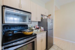 Kitchen with stainless steel appliances, light countertops, light wood finish cabinetry, and a textured ceiling - 