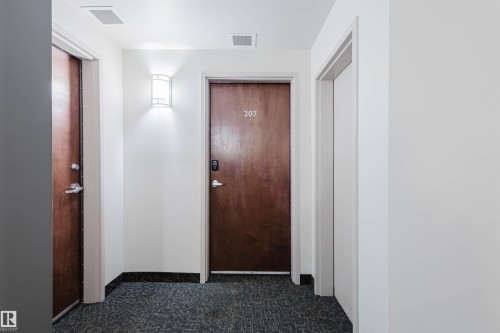 Hallway featuring baseboards and dark carpet - 207 9910 111 Street, Edmonton, AB - Indoor Photo Showing Other Room