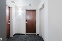 Hallway featuring baseboards and dark carpet - 