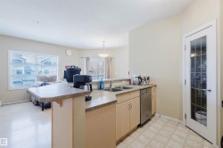 Kitchen with a peninsula, light wood finish cabinets, dishwasher, a kitchen breakfast bar, and light countertops - 