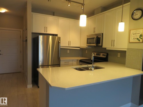 Kitchen featuring white cabinetry, stainless steel appliances, a peninsula, and pendant lighting - 415 2590 Anderson Way, Edmonton, AB - Indoor Photo Showing Kitchen With Double Sink
