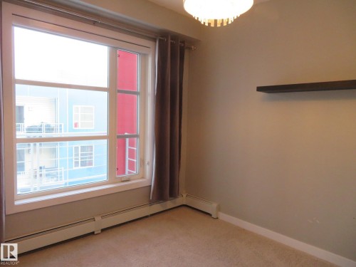 Empty room featuring baseboard heating and light colored carpet - 415 2590 Anderson Way, Edmonton, AB - Indoor Photo Showing Other Room