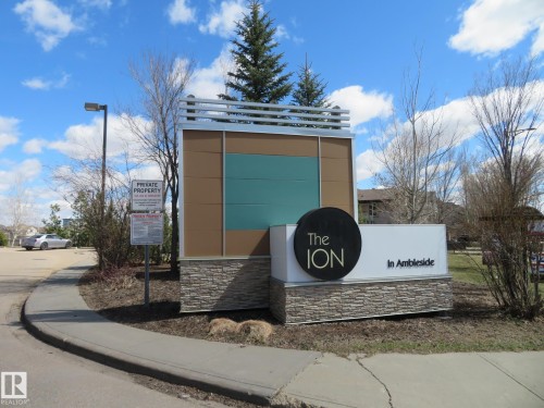 Modern community signage featuring stone accents, a contemporary metal and panel design, and integrated landscaping - 415 2590 Anderson Way, Edmonton, AB - Outdoor