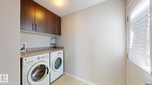 Laundry area featuring cabinet space, washing machine and clothes dryer, and light tile patterned floors - 1275 Chappelle Boulevard, Edmonton, AB - Indoor Photo Showing Laundry Room