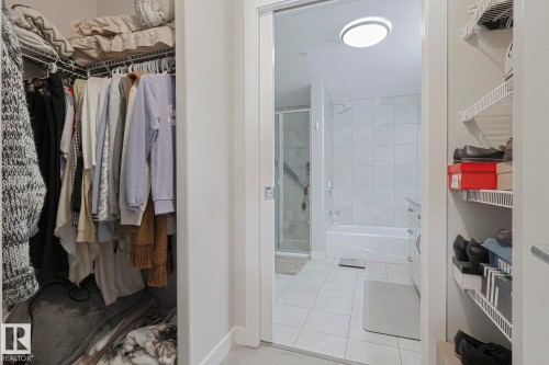 Bathroom featuring a spacious closet, a stall shower, light tile patterned floors, a tub to relax in, and vanity - 910 2755 109 Street, Edmonton, AB - Indoor