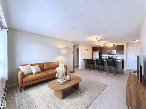 Living room with a baseboard heating unit and baseboards - 3308 9351 Simpson Drive, Edmonton, AB - Indoor Photo Showing Living Room