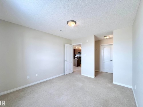 Unfurnished bedroom with light carpet and a textured ceiling - 3308 9351 Simpson Drive, Edmonton, AB - Indoor Photo Showing Other Room