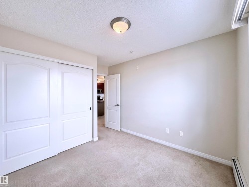 Unfurnished bedroom featuring baseboard heating, light colored carpet, a closet, and a textured ceiling - 3308 9351 Simpson Drive, Edmonton, AB - Indoor Photo Showing Other Room