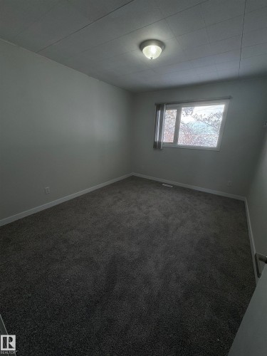 Empty room featuring dark colored carpet and baseboards - 4801 52 Avenue, Andrew, AB - Indoor Photo Showing Other Room