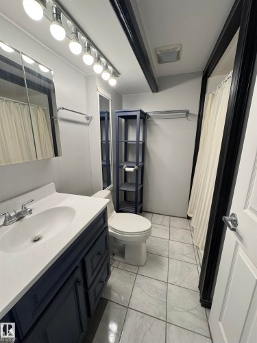 Bathroom featuring vanity, light marble finish floors, and a shower with shower curtain - 4801 52 Avenue, Andrew, AB - Indoor Photo Showing Bathroom