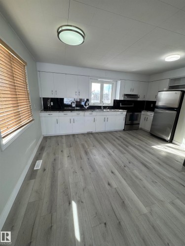 Kitchen with dark countertops, stainless steel appliances, white cabinetry, and light wood-style floors - 4801 52 Avenue, Andrew, AB - Indoor