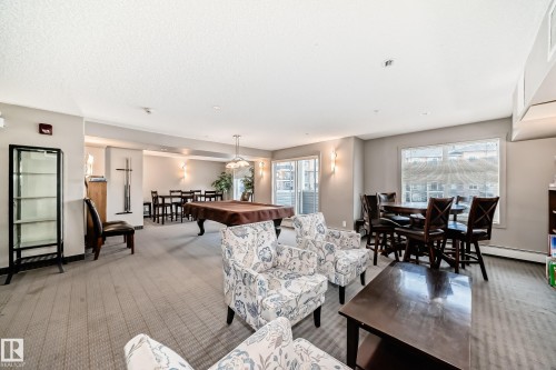 Carpeted Social room area featuring billiards table and a baseboard heating unit - 229 6076 Schonsee Way, Edmonton, AB - Indoor Photo Showing Living Room