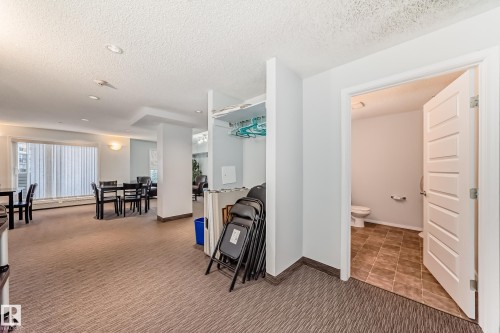 Social room area featuring carpet, a textured ceiling, and baseboard heating - 229 6076 Schonsee Way, Edmonton, AB - Indoor