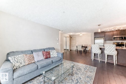 Living area with a textured ceiling and dark wood-style floors - 229 6076 Schonsee Way, Edmonton, AB - Indoor Photo Showing Living Room