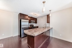 Kitchen with dark brown cabinets, appliances with stainless steel finishes, decorative light fixtures, light countertops, and a peninsula - 