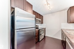 Kitchen featuring appliances with stainless steel finishes, light countertops, dark wood-style floors, a textured ceiling, and dark brown cabinetry - 
