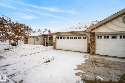 Single story home with stone siding, concrete driveway, a chimney, and an attached garage - 30 4 Heritage Way, St. Albert, AB - Outdoor