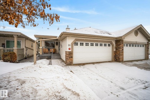 View of front of house featuring a chimney, stone siding, and a garage - 30 4 Heritage Way, St. Albert, AB - Outdoor With Facade