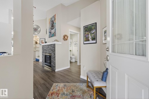 Foyer with dark wood-style flooring and a glass covered fireplace - 30 4 Heritage Way, St. Albert, AB - Indoor With Fireplace