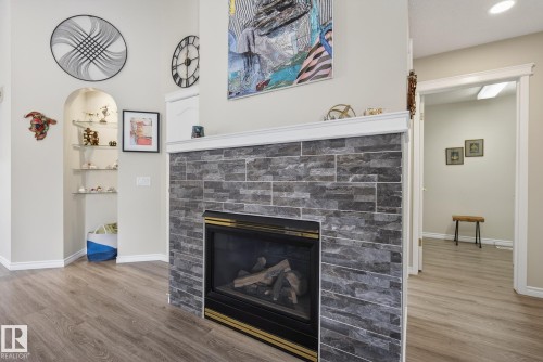 Detailed view of a glass covered fireplace and wood finished floors - 30 4 Heritage Way, St. Albert, AB - Indoor Photo Showing Living Room With Fireplace