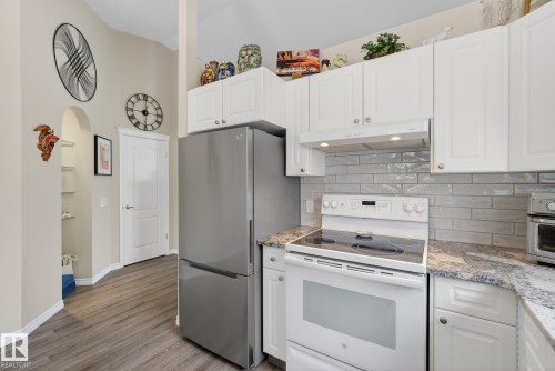 Kitchen with white range with electric cooktop, light stone counters, white cabinets, and a high ceiling - 30 4 Heritage Way, St. Albert, AB - Indoor Photo Showing Kitchen
