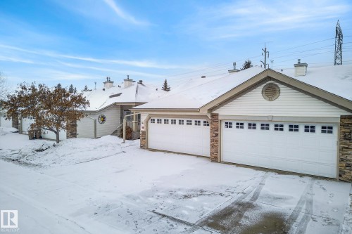 Ranch-style home featuring stone siding, a garage, an outdoor structure, and a chimney - 30 4 Heritage Way, St. Albert, AB - Outdoor