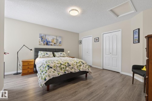 Bedroom with multiple closets, a textured ceiling, and wood finished floors - 30 4 Heritage Way, St. Albert, AB - Indoor Photo Showing Bedroom
