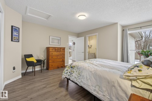 Bedroom with wood finished floors, a textured ceiling, and ensuite bathroom - 30 4 Heritage Way, St. Albert, AB - Indoor Photo Showing Bedroom