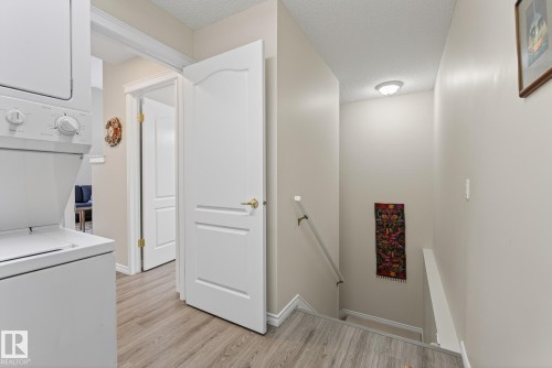 Laundry area featuring stacked washer / dryer, a textured ceiling, and light wood finished floors - 30 4 Heritage Way, St. Albert, AB - Indoor Photo Showing Laundry Room