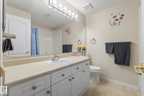 Bathroom featuring vanity, a shower with shower curtain, a textured ceiling, and light tile patterned floors - 30 4 Heritage Way, St. Albert, AB - Indoor Photo Showing Bathroom