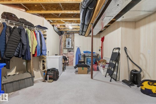 Unfinished below grade area with white fridge, electric panel, and wooden walls - 30 4 Heritage Way, St. Albert, AB - Indoor