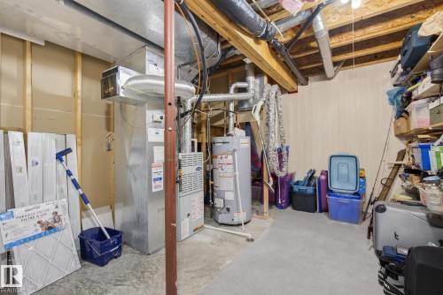 Unfinished basement featuring gas water heater, heating unit, and wooden walls - 30 4 Heritage Way, St. Albert, AB - Indoor Photo Showing Basement