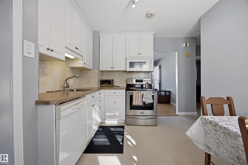 Kitchen with stainless steel appliances, white cabinets, tasteful backsplash, light colored counters, and rail lighting - 4209 116 Avenue, Edmonton, AB - Indoor Photo Showing Kitchen With Stainless Steel Kitchen With Double Sink