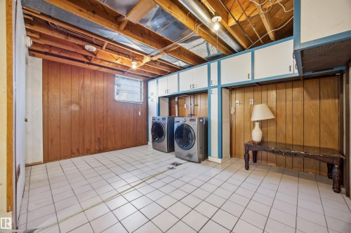 Laundry area featuring wood walls, washer and dryer, and cabinet space - 4209 116 Avenue, Edmonton, AB - Indoor