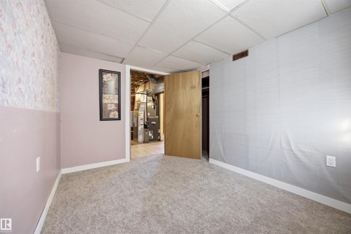 Basement bedroom with carpet flooring, a paneled ceiling, and wallpapered walls - 4209 116 Avenue, Edmonton, AB - Indoor Photo Showing Other Room