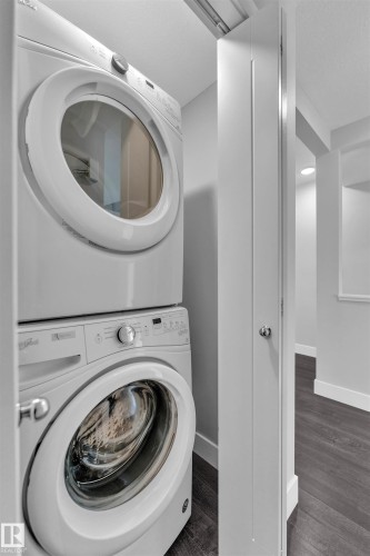 Laundry area featuring stacked washing machine and dryer, dark wood-style flooring, and a textured ceiling - #38 1508 105 St Nw, Edmonton, AB - Indoor Photo Showing Laundry Room