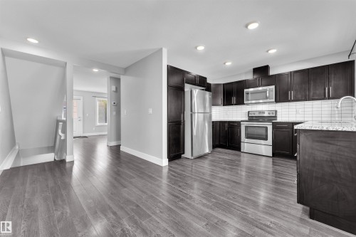 Kitchen with stainless steel appliances, light stone countertops, recessed lighting, decorative backsplash, and dark wood finish cabinets - #38 1508 105 St Nw, Edmonton, AB - Indoor Photo Showing Kitchen With Stainless Steel Kitchen With Upgraded Kitchen