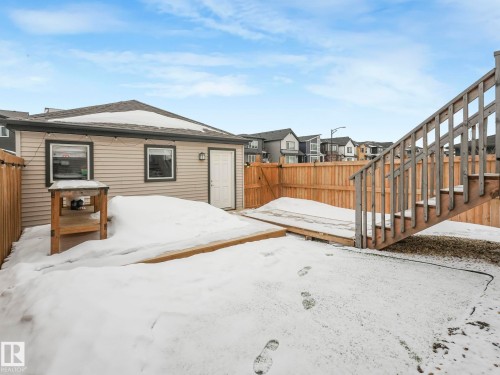 Snowy yard featuring a fenced backyard, a wooden deck, and a residential view - 1404 Podersky Link, Edmonton, AB - Outdoor With Exterior