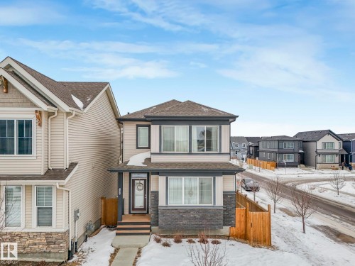 View of front facade with a residential view, a shingled roof, and stone siding - 1404 Podersky Link, Edmonton, AB - Outdoor