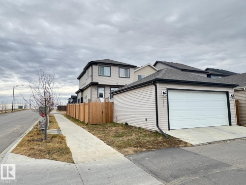 View of side of home featuring a shingled roof, an attached garage, and concrete driveway - 1404 Podersky Link, Edmonton, AB - Outdoor