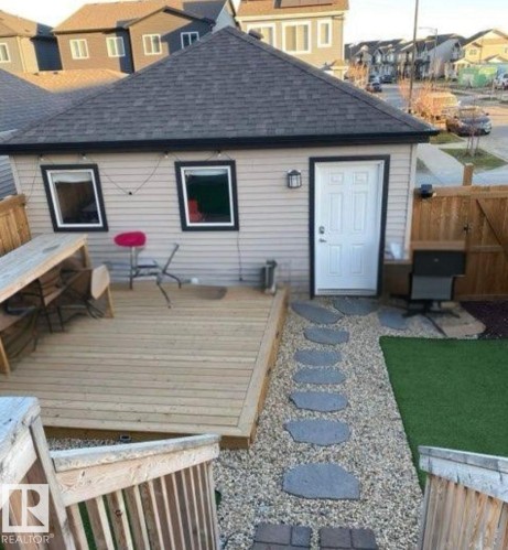 Back of property with roof with shingles, a wooden deck, a gate, and a residential view. Captured during summer - 1404 Podersky Link, Edmonton, AB - Outdoor With Exterior