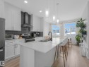 Kitchen featuring stainless steel appliances, light wood-type flooring, a center island with sink, and white cabinets - 1404 Podersky Link, Edmonton, AB  - Indoor Photo Showing Kitchen With Double Sink With Upgraded Kitchen 